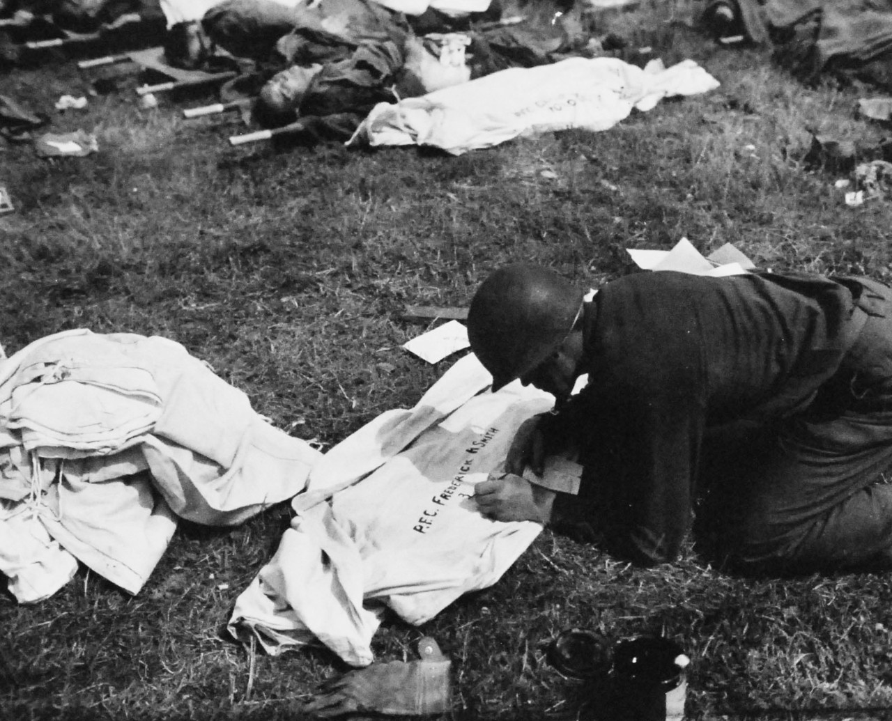 80-G-252670:   Normandy Invasion, June 1944.  Soldier lettering burial bag for American dead at temporary cemetery near Allied beachhead in France, 8 June 1944.  Official U.S. Navy Photograph, now in the collections of the National Archives.   (2014/10/28). 