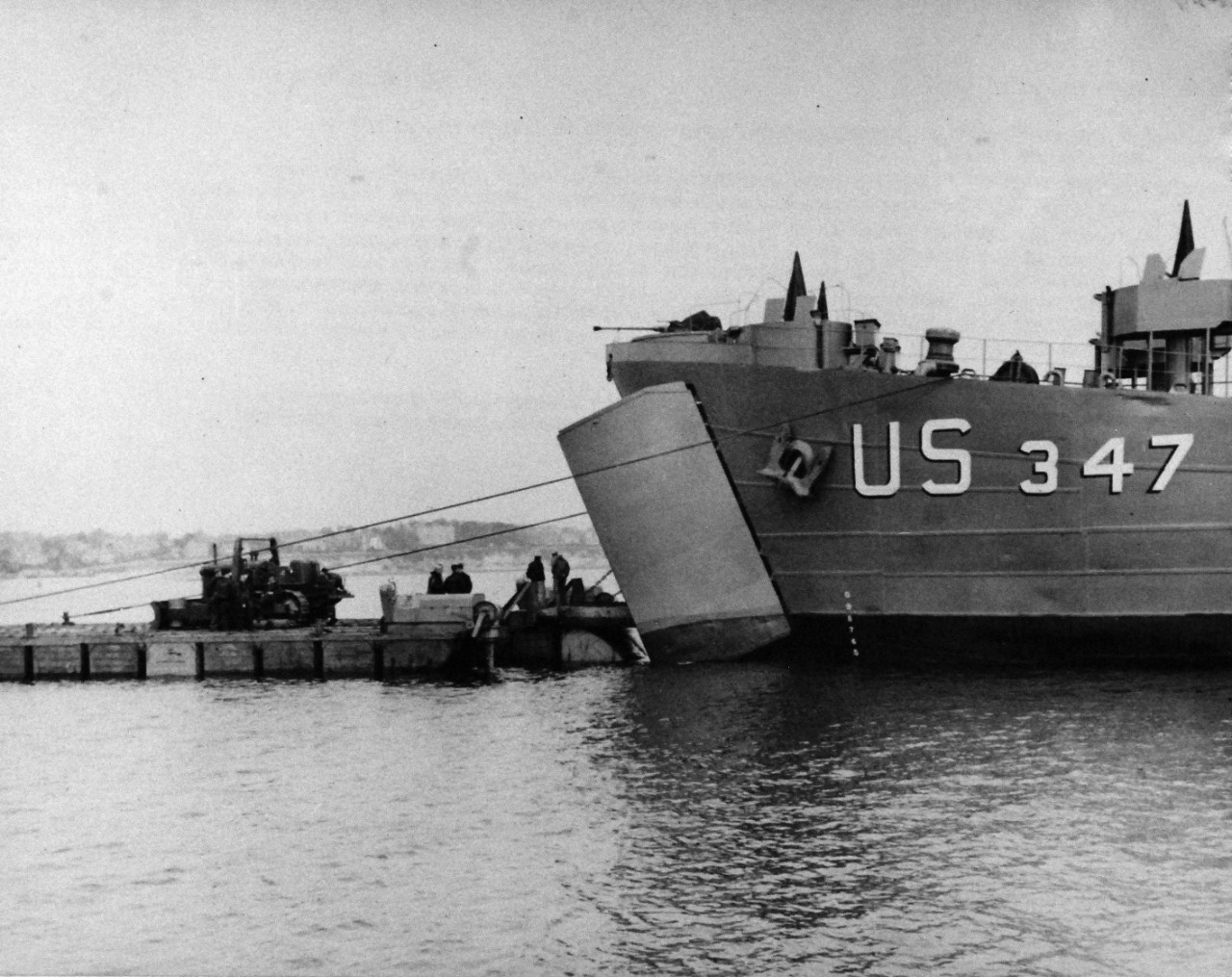80-G-45672:  Normany Invasion, Rhino Ferry, June 1944.    “Rhino Ferries,” designed by Navy’s Civil Engineering Corps to bridge the gap between ship and shore, are pontoons powered by two outboard motors of 143 hp and complete with steering gear.  Ferries are formed of 30 pontoons in length by 6’ wide, displaced approximately 275 tons, speed of about 4 knots and a shallower draft than LST’s.   Cargo begins to flow out of the open bow of LST 347 following its marriage to a Rhino Ferry.   Photograph released June 6, 1944.    Official U.S. Navy Photograph, now in the collections of the National Archives.  (2014/9/9).  