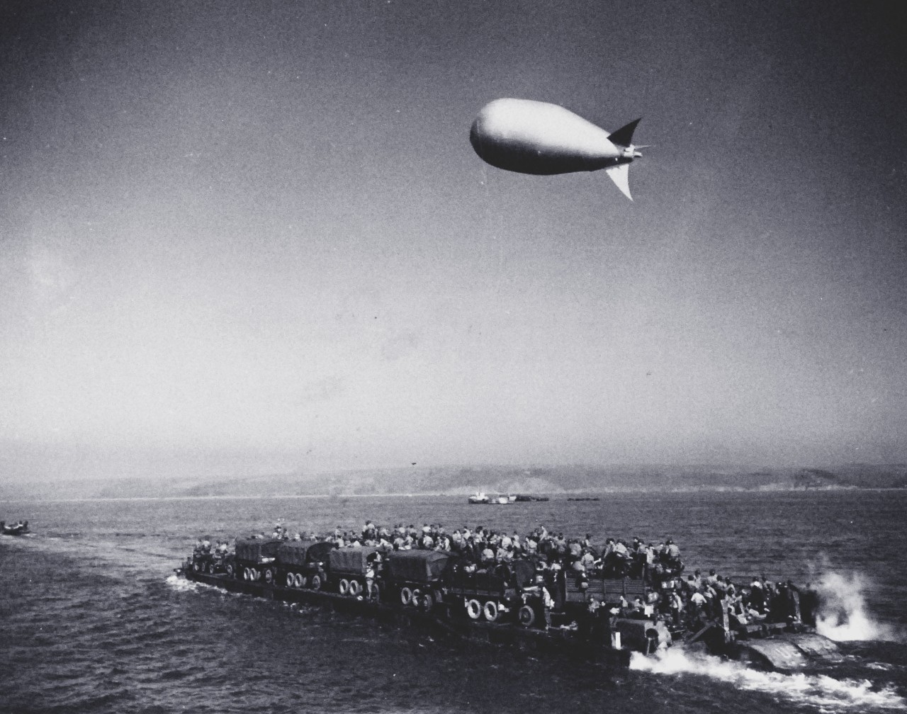 80-G-59405: Normany Invasion, Rhino Ferry, June 1944.      Normandy Invasion, June 1944.  Rhino ferry RHF-24, loaded with U.S. Army personnel and vehicles, undergoes tests off the English coast, prior to the Normandy invasion. Note the barrage balloon overhead.  Photograph released 10 June 1944, but taken well before that time.  Official U.S. Navy Photograph, now in the collections of the National Archives.    (2014/3/12).   