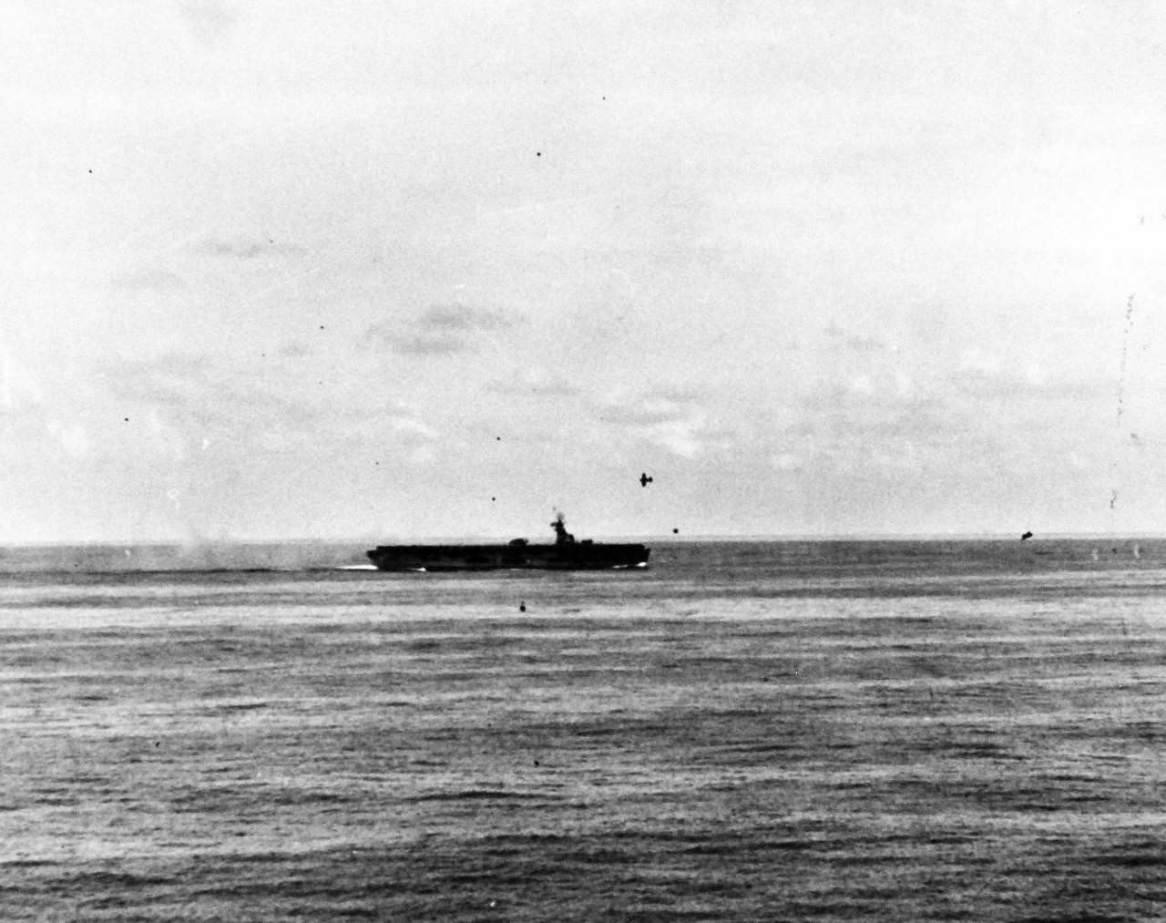 80-G-270665:  USS Sangamon (CVE-26), October 25, 1944.  Two Japanese “Zero” aircraft making suicide attacks on USS Sangamon (CVE-26) off Leyte Gulf, Philippines, as seen from USS Suwannee (CVL-27).  One Japanese near miss near bow.  Trailing Japanese turned away and was shot down by our fighters. Official U.S. Navy Photograph, now in the collections of the National Archives.  