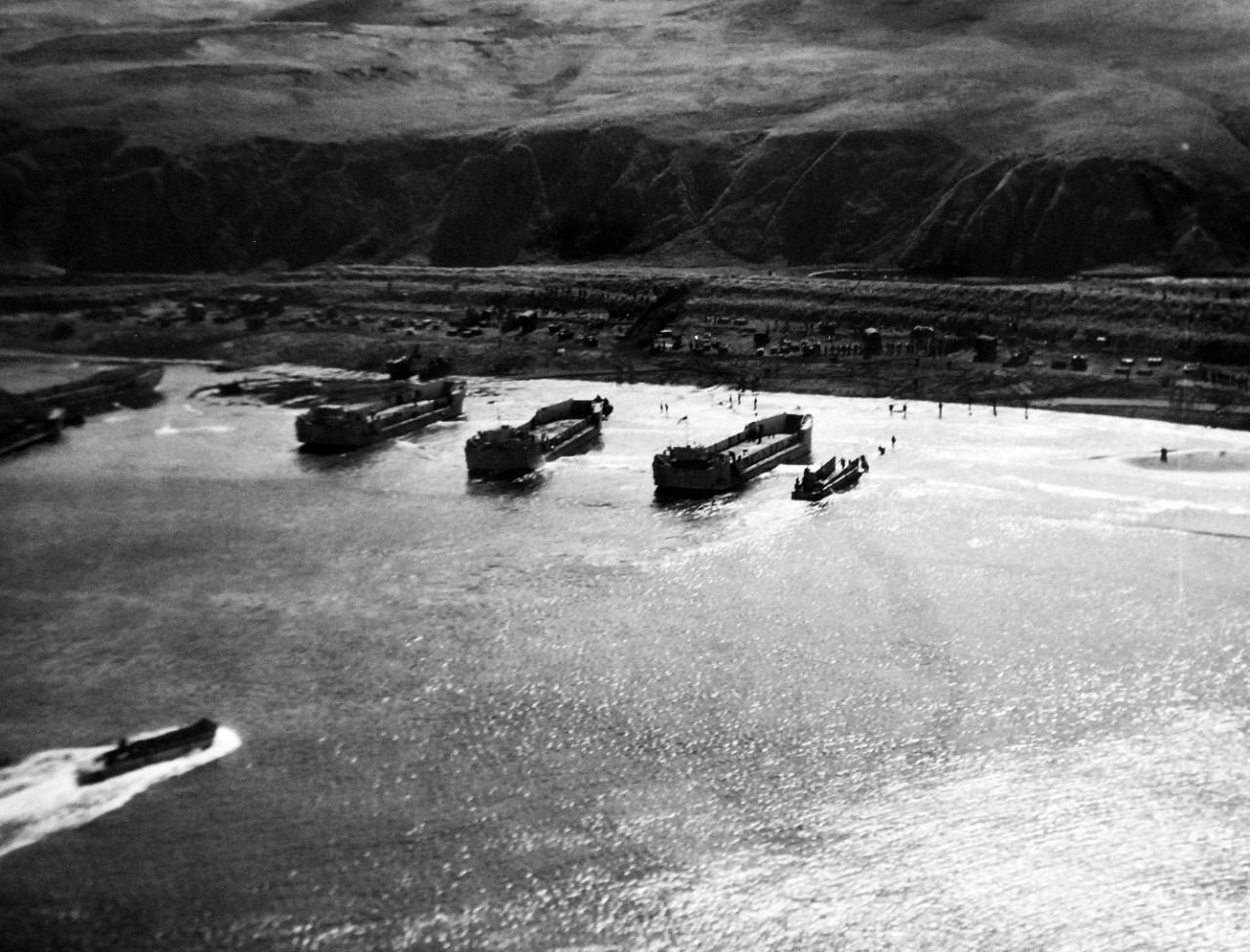 LC-Lot-803-10:  Aleutian Islands Campaign, June 1942 - August 1943.   Allied Invasion of Kiska, August 15-24, August 1943.  First photographs, landing operations, Kiska, August 15, 1943.   This remarkable photograph was taken by a US Navy Vega PV-1 “Ventura”, a patrol bomber operating as part of the air cover for the task force.   United States and Canadian troops swarming ashore from landing barges on a stretch of beach along the northwest coast of Kiska.  The man can be seen moving up the hillside like ants.  At this time, they did not know whether the Japanese were “playing possum” or not.  The barges backing away are the familiar LCTs, LCMs, and LCPs, which were also used in the Attu and Sicily Campaigns.  U.S. Navy photograph, released August 23, 1943.  Photographed through Mylar sleeve.  Courtesy of the Library of Congress.  (2015/11/06).