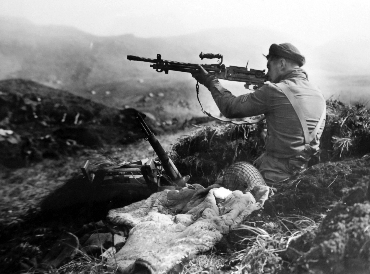 LC-Lot-803-2:  Aleutian Islands Campaign, June 1942 - August 1943.  Allied Invasion of Kiska, August 15-24, August 1943.    Kiska Landing, August 15, 1943.  Japanese Machine Gun Gets A Try-Out.  Squinting down the sights of a Japanese machine gun found in a trench on Kiska Island is this member of the joint American-Canadian landing force.  Beside him lies a discarded Japanese pack, coat, and helmet.  U.S. Navy photograph.  Photographed through Mylar sleeve.   Courtesy of the Library of Congress.   (2015/11/06).