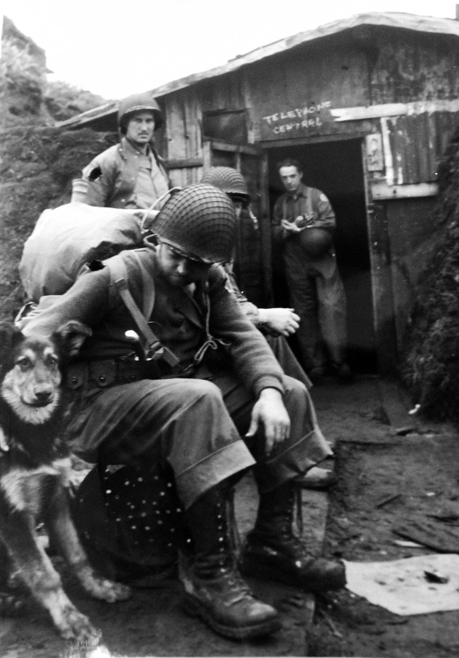 LC-Lot-803-6:  Aleutian Islands Campaign, June 1942 - August 1943.   Allied Invasion of Kiska, August 15-24, August 1943.   Kiska Landing, August 15, 1943. Japanese Dog Takes to New Masters.  Left on Kiska Island by the Japanese, this dog soon found new friends among the American forces.  This was a first day scene outside the Japanese central telephone control shack.  Americans found it in such good condition that they took over and plugged in.    Photograph released August 28, 1943.  U.S. Navy photograph.  Photographed through Mylar sleeve. Courtesy of the Library of Congress.  (2015/11/06).