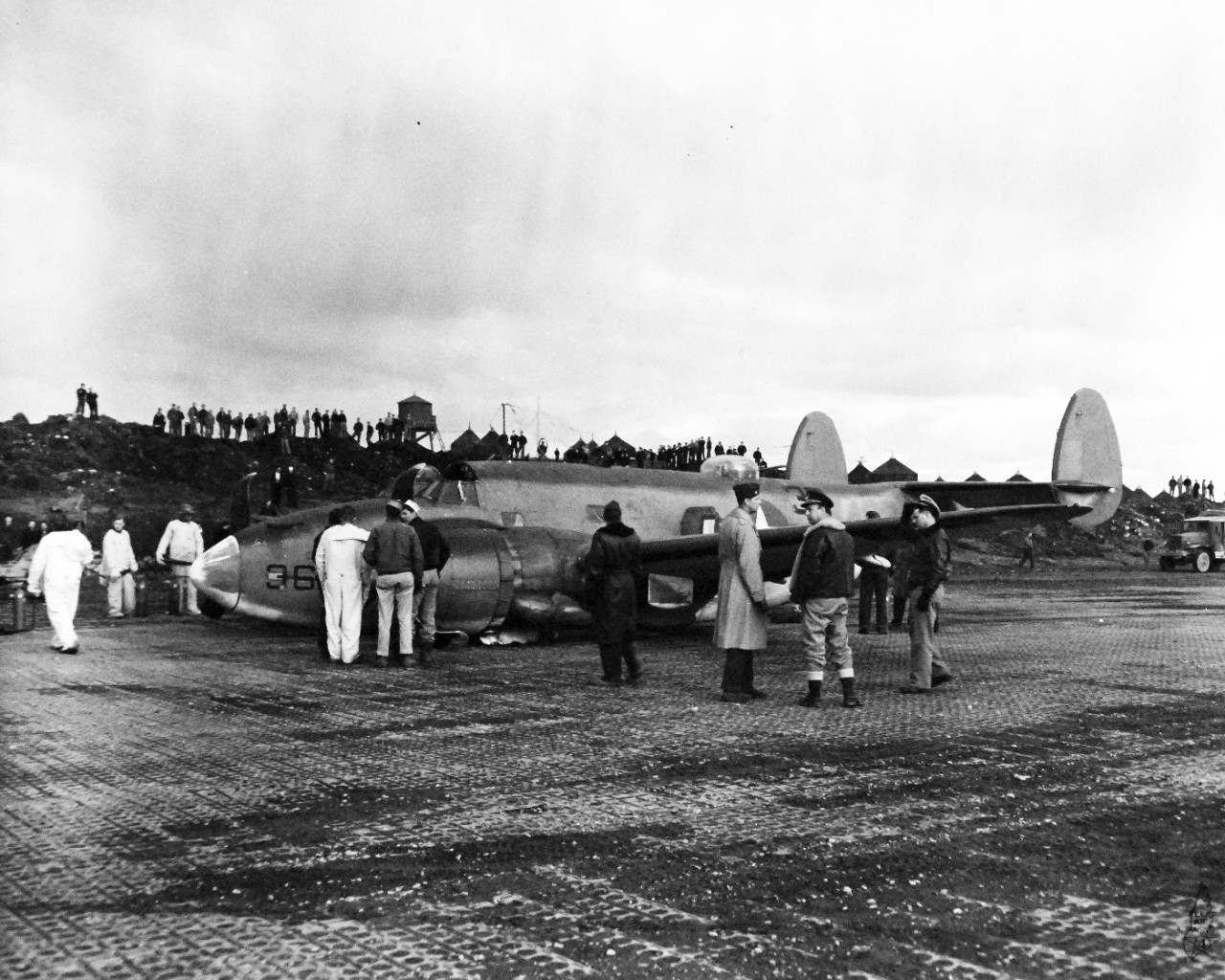 80-G-239344:  Attu, Alaska, May 1944.    Crash landing of a PV-1 (Bu #33433) returning to Attu Island, Alaska, from encounter with Japanese auxiliary vessel in the North Pacific.  Lieutenant Q.E. Norem USNR, pilot and Lieutenant Junior Grade G. M. Tambs, USNR, co-pilot was killed during encounter.  Shown:  Officers discussing removal of crashed plane from runway, released May 19, 1944.    U.S. Navy photograph, now in the collections of the National Archives.  (2017/03/07).