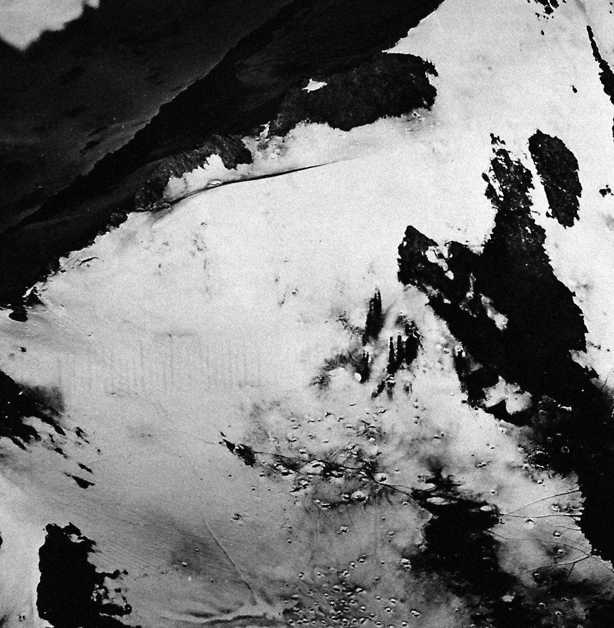 80-G-41840:   Aleutian Islands Campaign, June 1942 - August 1943.   Battle of Attu, May 11-29, 1943.    Aerial of Japanese positions on Attu, Aleutian Islands.  United States Navy photographers flew over the Japanese position on Attu Island, making pictures at will during the last days of the organized Japanese resistence there.  These two pictures were made as the foe was being driven back and into the Chicagof Harbor valley, his last stronghold.   Along the crest and in the bowl (foreground) are Japanese trails and foxholes in the snow, as well as holes from American firing.  The foe was making a stand along the ridge before being driven back to Chicagof Harbor valley, which is straight down from the ridge (upper left).  The scene was southwest of Chicagof Harbor, looking northeast.  Photographed May 24, 1943.  U.S. Navy Photograph, now in the collections of the National Archives.  (2016/05/10).