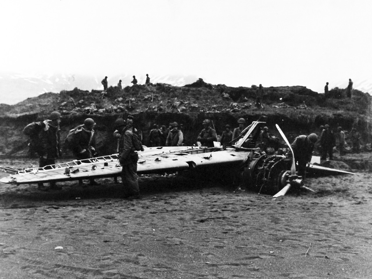 80-G-54503: Aleutian Islands Campaign, June 1942 - August 1943.  Battle for Attu, May 1943.    American soldiers landing at Holtz Bay find a Japanese victim of Army Air Corps marksmanship.  This float-type Zero had been machine-gunned several days before the landing by attacking U.S. planes.  The Japanese pulled the damaged ship ashore and turned it over on its back.  U.S. troops in the landing party survey the craft.   Photograph, May 11, 1943.   Official U.S. Navy photograph, now in the collections of the National Archives.   (2016/07/19).
