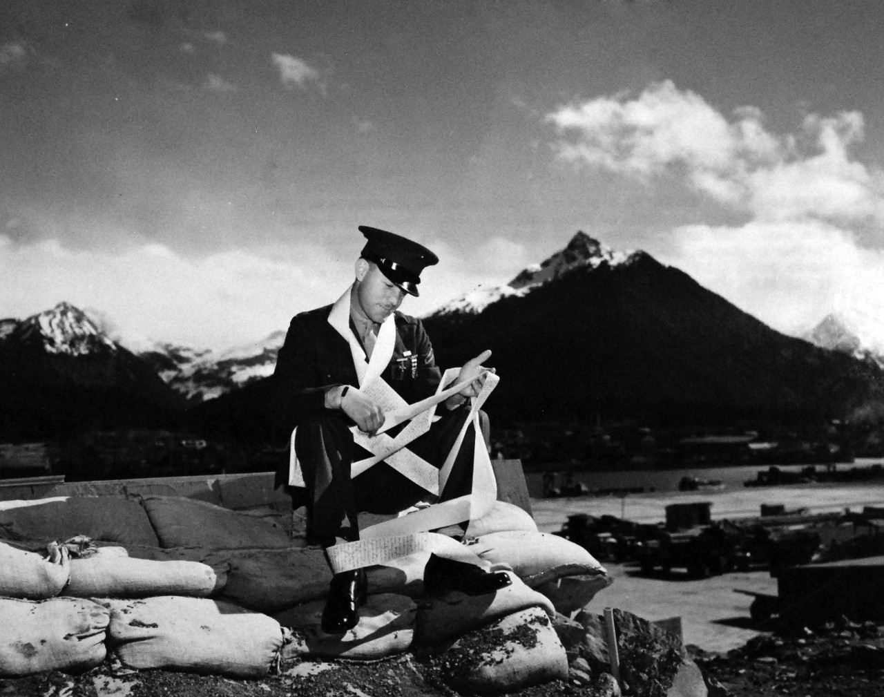 80-G-41502:   U.S. Naval Operation Base, Sitka, Alaska.     Sitting on a pile of sandbags at Sitka, Alaska, Private First Class Audrey Hopkins Hall, USMC, reads his letter from home.  It is 21 feet and 3.5 inches long.  It was started by his sister, circulated among his relatives and completed by his wife, Eleanor, a welder in a war plant, 18 March 1943.    Sitka was established in 1939.   Official U.S. Navy Photograph, now in the collections of the National Archives.  (2014/6/12). 