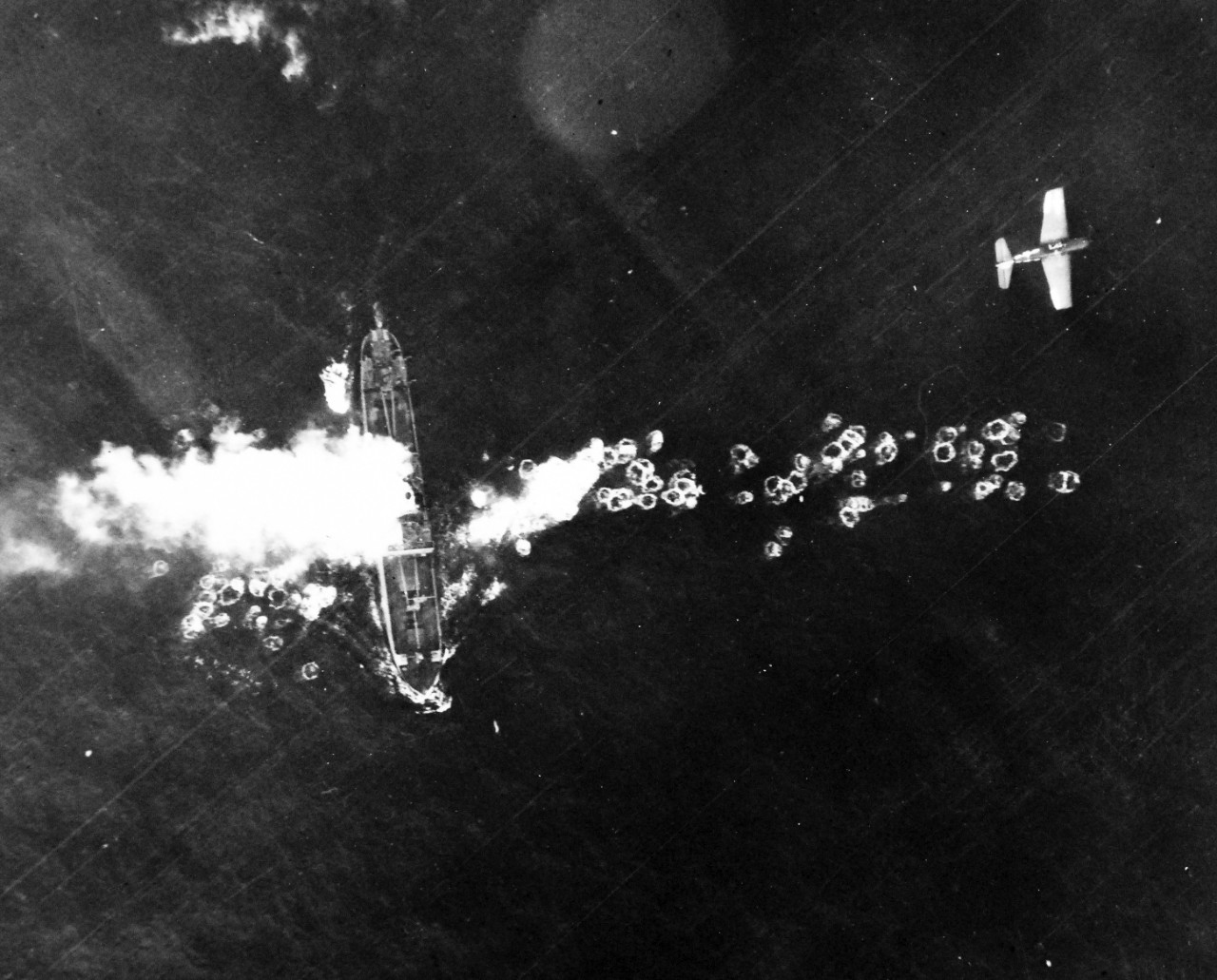 80-G-490117:  Raids on Japanese Home Islands, July  15, 1945.   Japanese freighter caught by carrier-based aircraft of the Third Fleet near Fukuya Wan, Hokkaido, Japan, starts to burn following a strafing run by F6F “Hellcat” plane seen near top of photograph, July 15, 1945.  U.S. Navy Photograph, now in the collections of the National Archives. (2015/12/08).