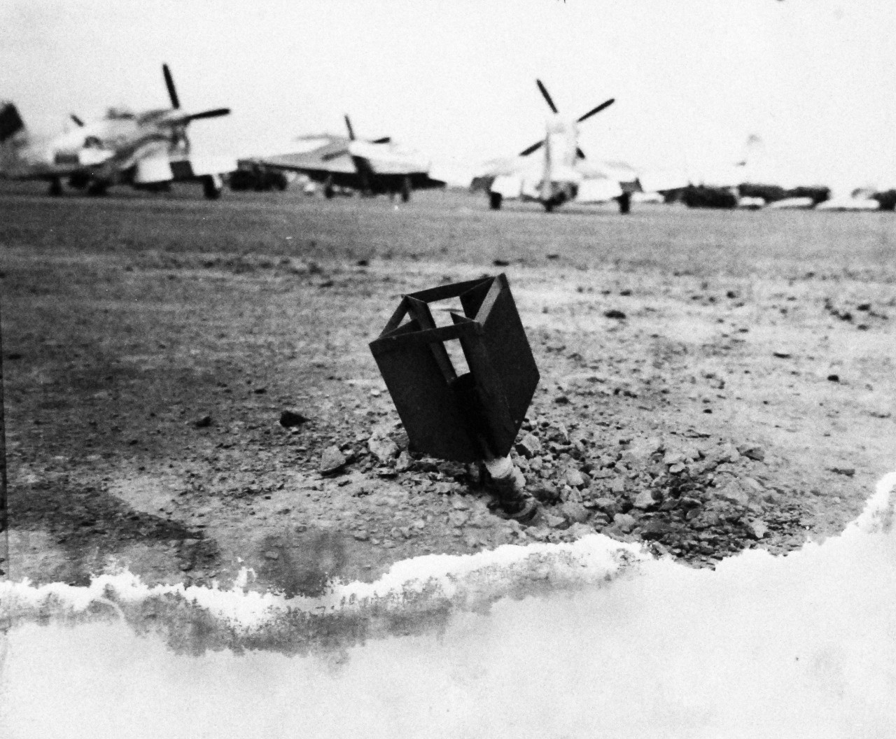 127-GW-304-114274:  Battle for Iwo Jima, February-March 1945.   Tail fin of a Japanese rocket sticking out of the airfield.  Photographed by Altfather, March 10, 1945.  U.S. Marine Corps photograph, now in the collections of the National Archives.  (2016/02/17).   This photograph is damaged.  