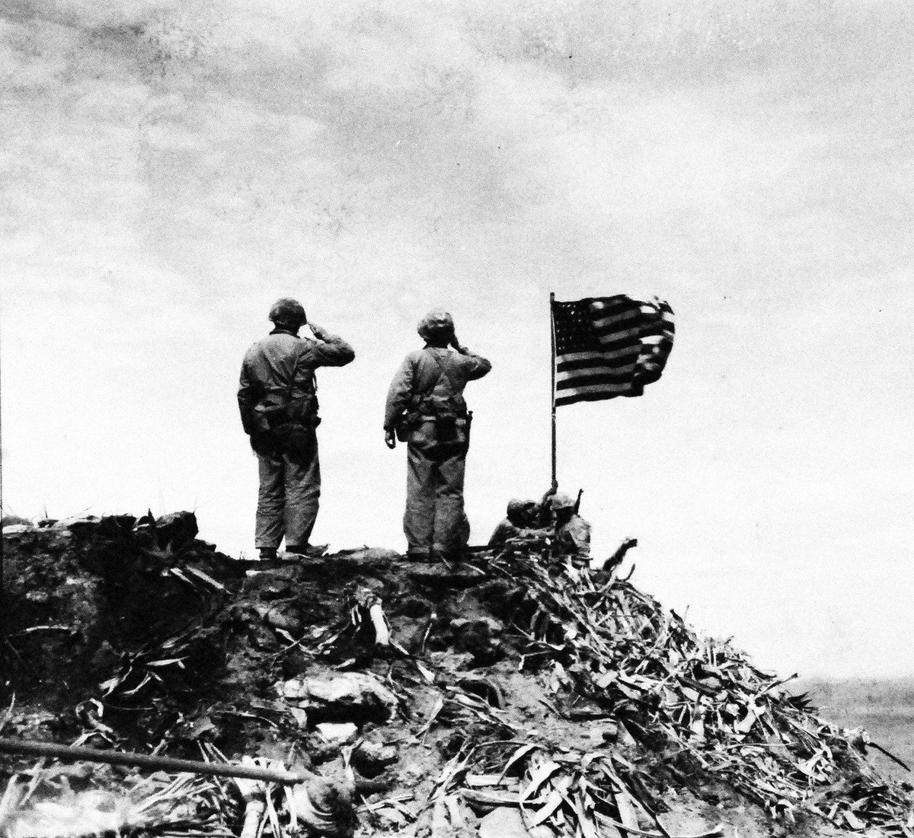 127-GW-319-112719: Iwo Jima Operations,  February 1945.  Two Marine render a salute to the flag as it is raised on Mount Surbachi by Marines of the Fifth Marine Division.   Photographed by Bob Campbell, February 23, 1945.   Official U.S. Marine Corps Photograph, now in the collections of the National Archives.  (2016/09/06).