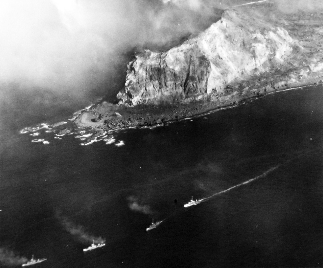 80-G-307186: Battle for Iwo Jima, February 27, 1945. Iwo Jima covered with bomb craters from incessant attack by carrier based planes.  Note smoke rising and aerial field in background.  Photographed by plane from USS Saginaw Bay (CVE-82).   U.S. Navy photograph, now in the collections of the National Archives.  (2016/09/06).