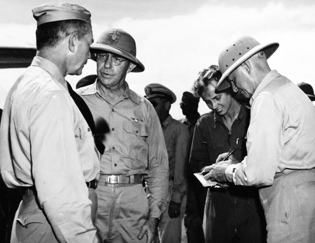208-PU-70A-5:   Battle for Iwo Jima, February 1945.   Secretary Forrestal Confers with Admiral Nimitz and Vice Admiral Turner.   Secretary of the Navy James Forrestal talks with Vice Admiral Richmond K. Turner, USN, Commander of the Iwo Jima expeditionary force, at the airport at Saipan, just after the Secretary’s arrival by plane from Washington, D.C.   At the right, Second Lieutenant James F. Perlowin gets an autograph from Fleet Admiral Chester W. Nimitz, USN, Commander-in-Chief, Pacific Fleet and Pacific Ocean Areas.  Secretary Forrestal watched the invasion of Iwo Jima from Vice Admiral Turner’s Flagship and went ashore on the volcanic island to view at first hand the fiery battle between Marines and Japanese for control of that important stepping stone to Tokyo.   Photograph released February 25, 1945.   Office of War Information Photograph, now in the collections of the National Archives.  (2016/03/29).