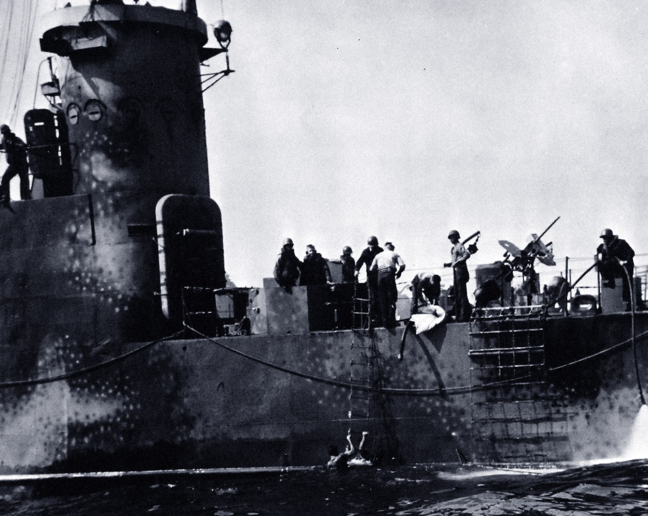 80-G-304828:  Battle for Iwo Jima, February 19, 1945.  Crewmen of LSM as they stuffed their mattresses into a hole blown in the side of their craft off Iwo Jima to keep her afloat long enough to reach the beach.  The hose at the right is from a pump, trying to keep abreast of the rising water in the hole.  Photograph released February 26, 1945.  U.S. Navy Photograph now in the collections of the National Archives.  (2016/01/19).