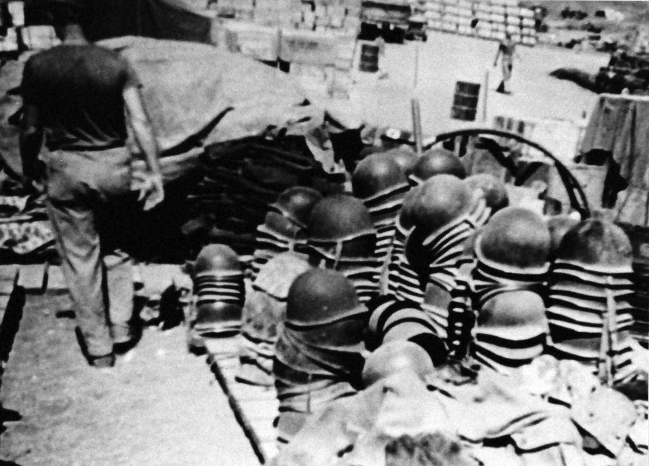80-G-49220:   Battle for Iwo Jima, February 19, 1945.   Personal effects of Marines who fell in battle on Iwo Jima.   A U.S. Marine paces past the piles of helmets.   Photograph released May 24, 1945.  Official U.S. Navy Photograph, now in the collections of the National Archives.  (2014/12/02).  