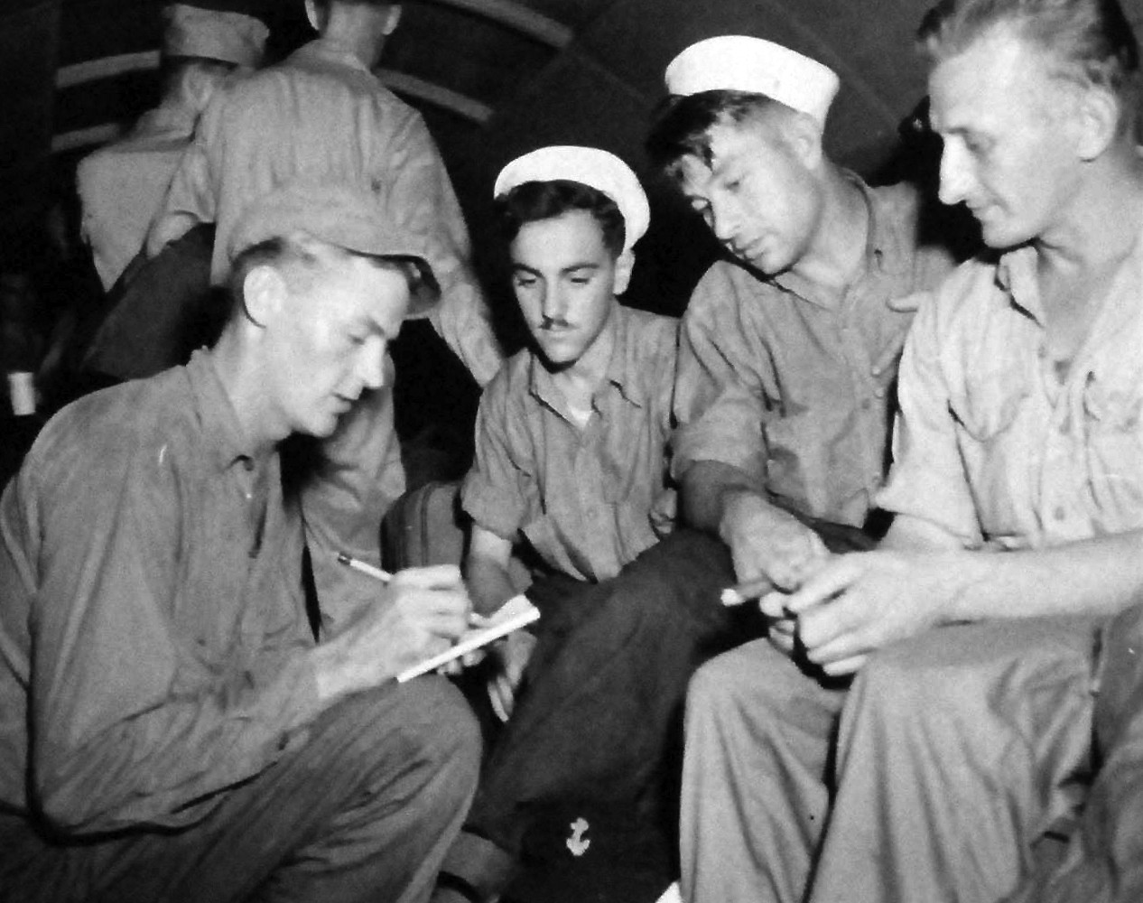 80-G-339126:   Allied Prisoners of War, 1945.   The prisoners are just returning from internment in Japan at Agana, Guam.  Shown left to right:  Photographer’s Mate Third Class Marine F. Rhode interviewing AMM3 Murray Glasser; Coxswain Earl King; and BM1 Raymond J. Jakubielski, September 4, 1945.   Photographed by D.M. Edinger.  Official U.S. Navy photograph, now in the collections of the National Archives.  (2013/08/14).   Note, original photograph is small.  