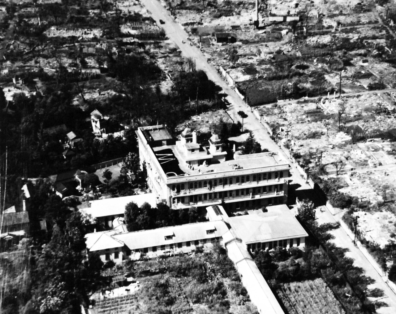 80-G-344489:   Allied Prisoner of War Building, Tokyo, Japan, 1945.    Prisoner of War building at Tokyo, Japan, with people on the roof.  Taken by plane from USS Essex (CV-9), PHOM1/C P.J.Madden, PHOM3/C H.C. Stoker, August 28, 1945. Official U.S. Navy photograph, now in the collection of the National Archives.  (2014/05/22).    The original photograph is small.   