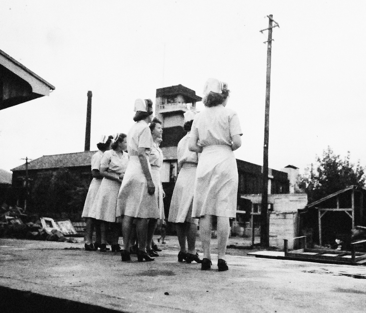 80-G-346550:   Prisoners of War, 1945.    U.S. Navy Nurses from USS Haven (AH-12) wait at the railroad station Nagasaki, Kyushu, Japan, for the first liberated Prisoners of War to arrive from Koyagi Island Prison Camp.  In the background is the customs house.  Photographed by crew of USS Chenango (CVE-28), September 13, 1945.  Official U.S. Navy photograph, now in the collection of the National Archives.  (2014/11/5).    Note, the original photograph is about 1” x 1” in size.   