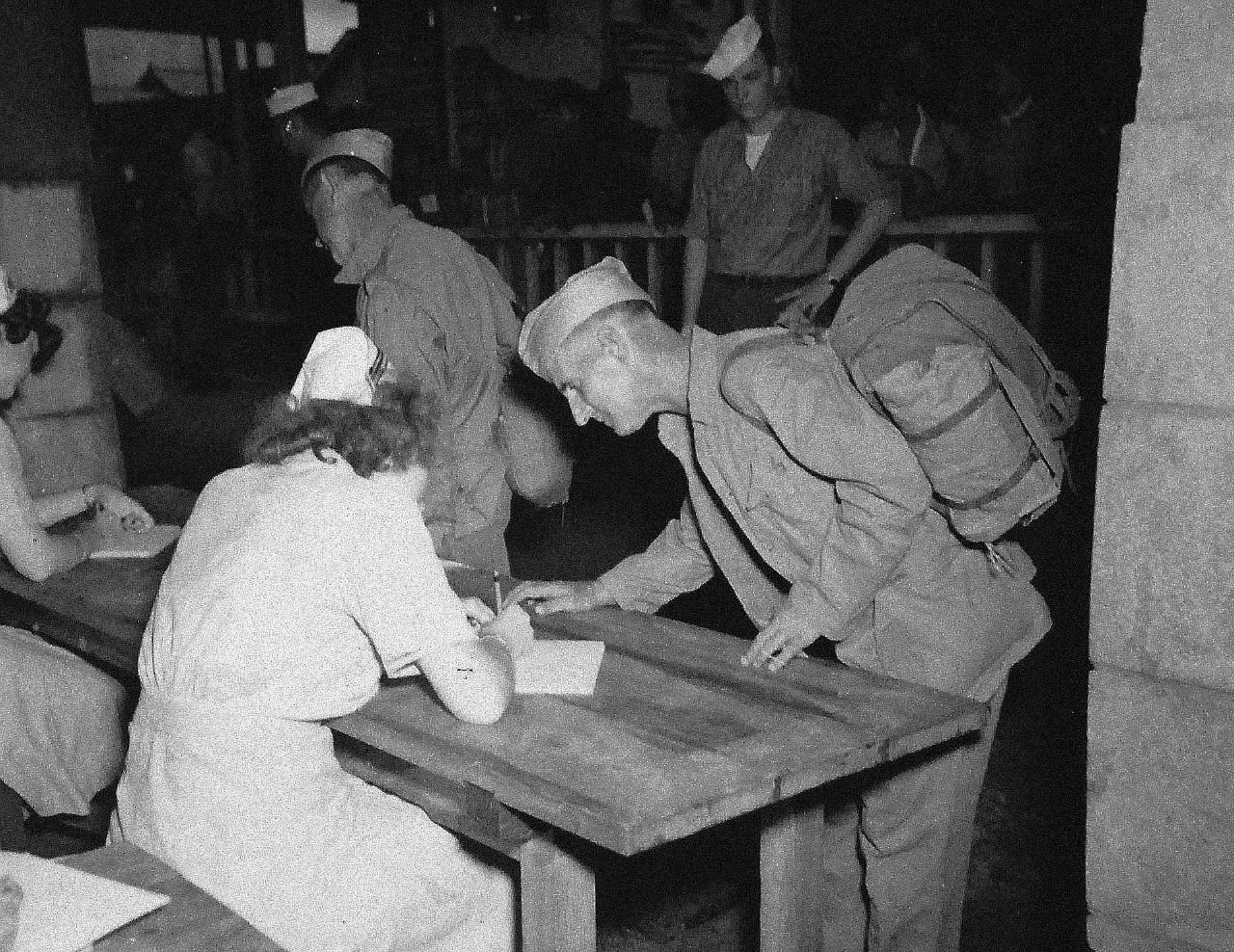 80-G-346552:  Allied Prisoners of War, 1945.    J. Payne, who was a British Prisoner of War on Koyagi Island prison camp, is now going through the liberation routine at the Nagasaki Evacuation Center.  He is giving his history to nurse Harriet Fly, which is the first step at the processing center. Photographed by crew of USS Chenango (CVE 28), 13 September 1945.  Official U.S. Navy photograph, now in the collections of the National Archives.   (2014/11/5).