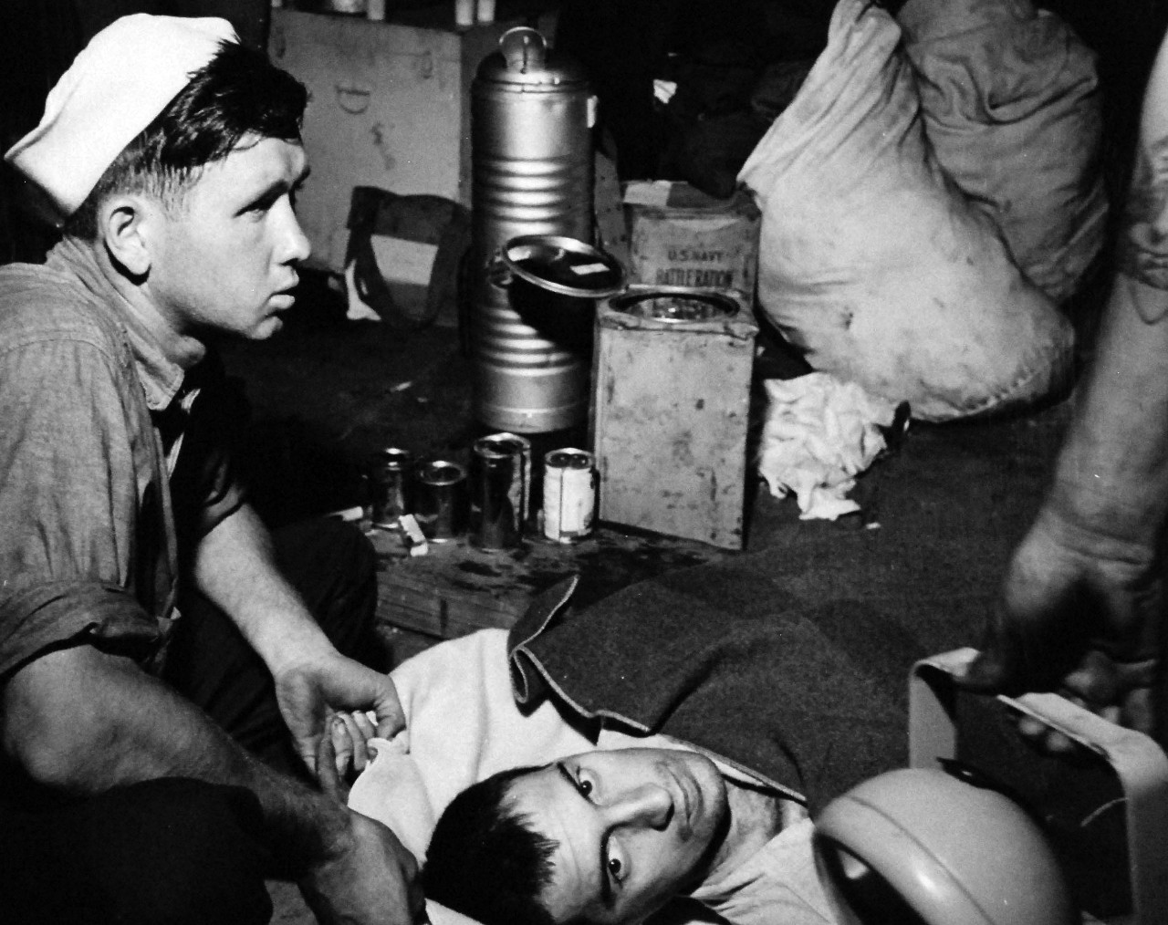 80-G-490458:   Allied Prisoners of War, 1945.   Allied prisoners of war suffering from malnutrition and other disorders as seen after their rescue from the Omori camp, Tokyo area, by a U.S. Navy rescue mission headed by Commander Roger Simpson and Commander Harold Stassen.  Treatment of prisoners was described as inquisitional form of barbarism.  Shown is an Allied prisoner of war too emaciated to walk and is carried on board a small craft to be transported to a U.S. Navy hospital ship in Tokyo Bay, August 30, 1945.  Emergency medical and food supplies can be seen at the left.   Official U.S. Navy photograph, now in the collections of the National Archives.  (2014/05/29).    The original is a small photograph.   