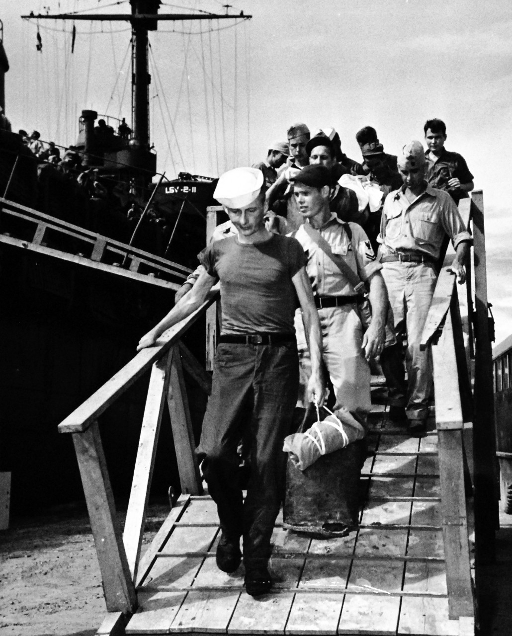 80-G-490496:   Allied Prisoners of War, Guam, 1945.  Liberated American Prisoners of War at Guam, Mariana Islands, after disembarking from USS Ozark (LSV-2) and going down gangplank.  Official U.S. Navy photograph, now in the collections of the National Archives.  (2014/05/29).    The original is a small photograph.   