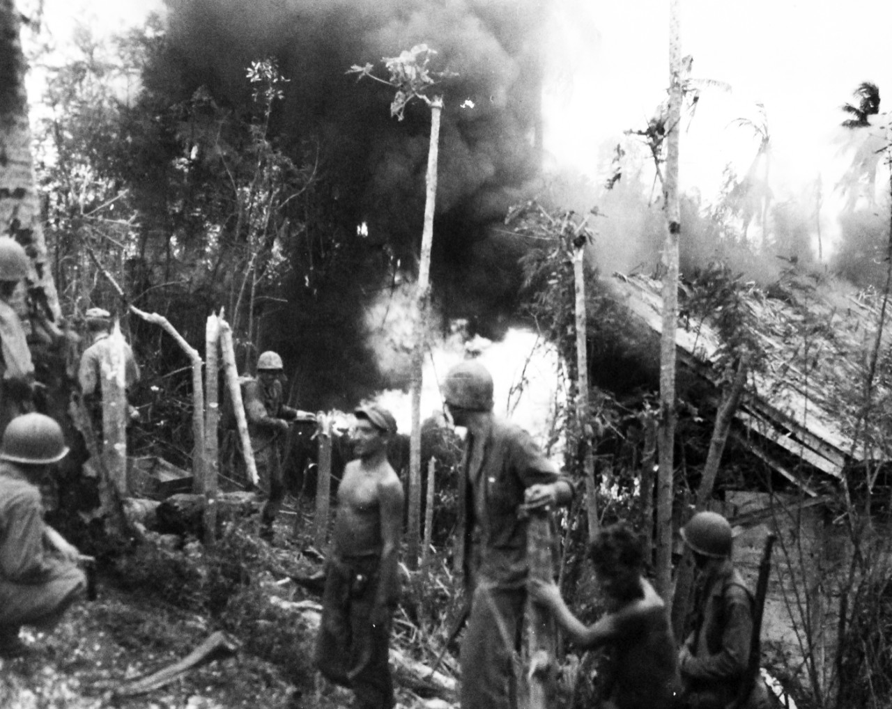 80-G-239424:  Invasion of Guam, July 21-August 10, 1944.   U.S. Marines turned away from the intense heat, when they used a flame thrower to drive the enemy from a building on Guam.  The Japanese – who lived – dashed out a rear door and were shot down by other Marines using automatic rifles, released August 3, 1944.    Official U.S. Navy Photograph, now in the collections of the National Archives.  (2017/03/07).