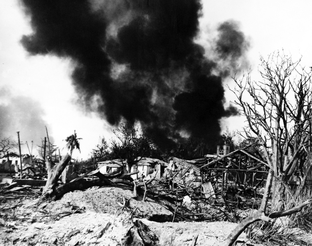 80-G-287181:   Invasion of Saipan, June-July 1944.    General destruction ahead of Marine front lines on Saipan showing a fire and shell crater,  July 2, 1944.     Photographed by USS Indianapolis (CA-35) photographer.   Official U.S. Navy photograph, now in the collections of the National Archives.  (2017/03/21).  