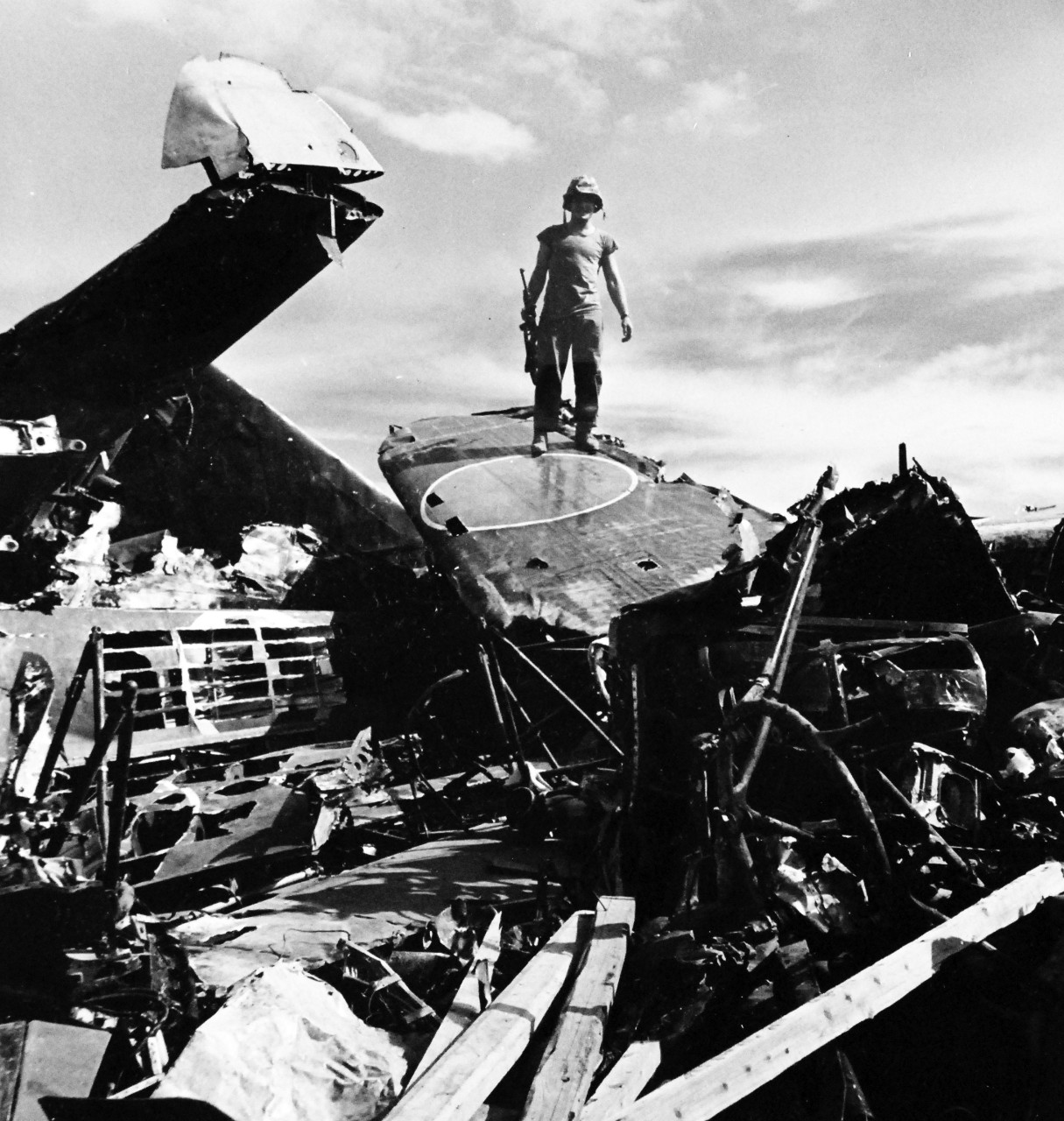 80-G-475140:  Invasion of Saipan, June-July 1944.  U.S. Marine stands on battered wreckage of Japanese bomber on Saipan.   Photographed by Lieutenant Paul Dorsey, July 1944, TR-10219.      Official U.S. Navy photograph, now in the collections of the National Archives.   (2017/03/15).