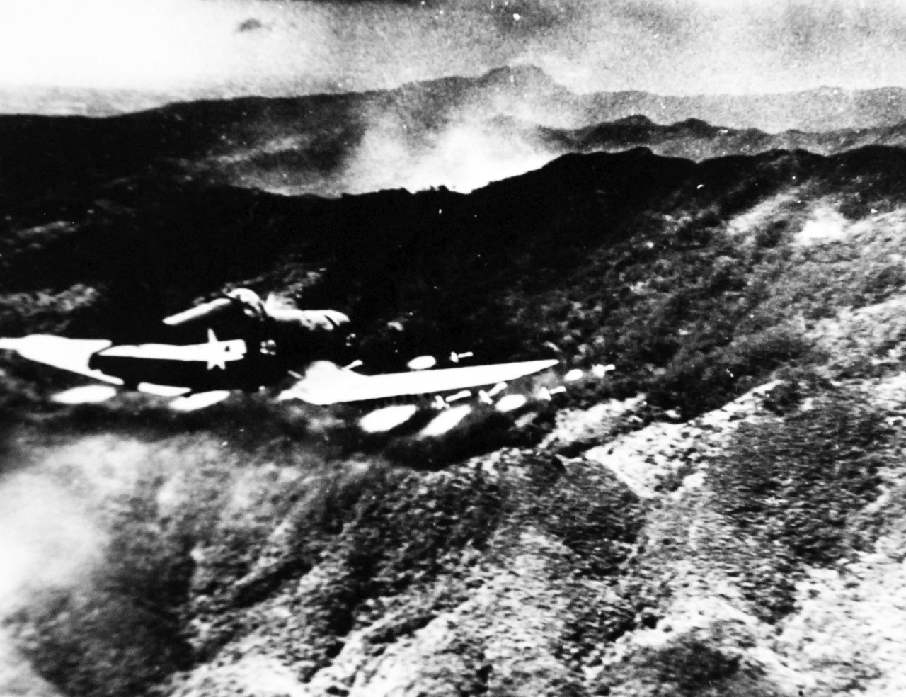 127-GW-520-129356A:  Okinawa Campaign, April-June 1945.   “Rockets Away”.  Making a run over Japanese positions on Okinawa, a Marine Corsair cuts loose eight five-inch rockets, comparable to a full broadside from a destroyer.  This unusual photograph was made by Marine First Lieutenant David D. Duncan from a plexi-glass nosed belly tank slung under the wing of a P-38.  The concussion from the rocket blast blew the photo ship over on its right wing and almost caused it to crash into the target area, undated.  Official U.S. Navy Photograph, now in the collections of the National Archives.   (2014/6/25). 