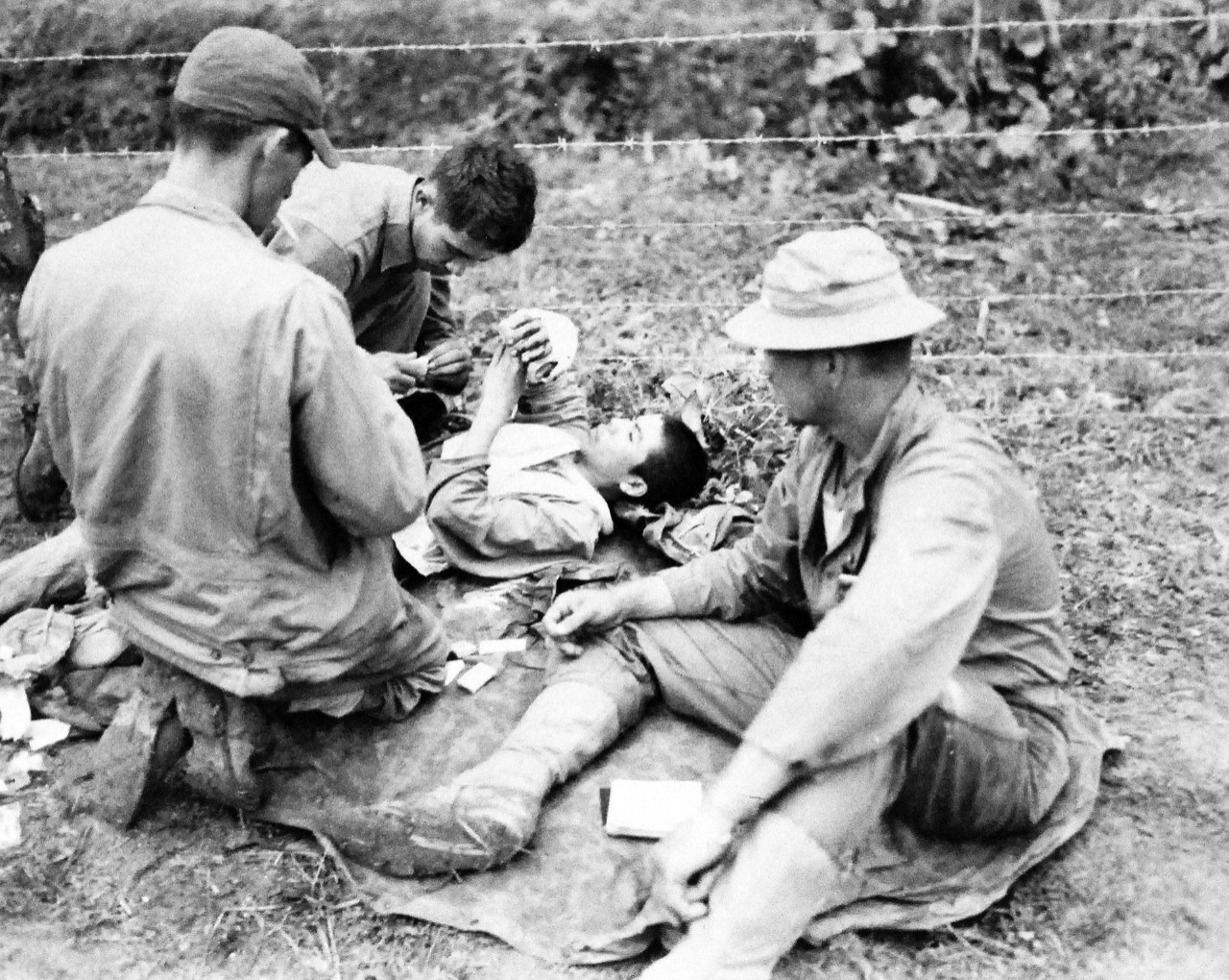 127-GW-666-119801:  Okinawa Campaign, April-June 1945.   Japanese prisoner given first aid.  Shown (left to right):  PHM1/C F.M Dish, USN, Japanese prisoner, Corporal, John S. Rachuneh and center back to camera, Lieutenant J.H. Murphy, MC, USN.     Photographed by Goldberg, April 8, 1945.   Official U.S. Marine Photograph, now in the collection of the National Archives.  (2014/7/23). 