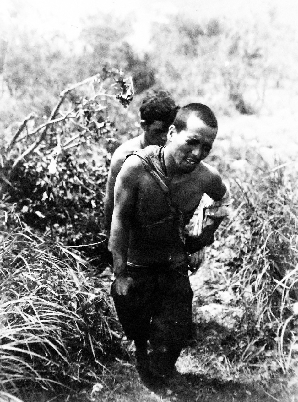 127-GW-666-128729:   Okinawa Campaign, April-June 1945.   Wounded Japanese soldier taken from blasted cave is brought up Hill by a Marine, Mezado Ridge, Okinawa, 17 June 1945.   Official U.S. Marine Photograph, now in the collection of the National Archives.  (2014/7/23). 