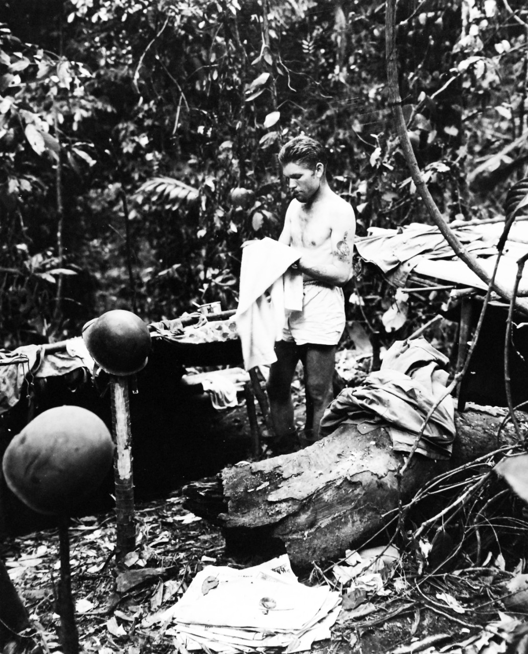 80-G-205289:  Bougainville Campaign, November 1943- August 1945.  Platoon Sergeant Ned T. Perry, USMC, cleans up during a lull between battles on Marine beachhead in northern Solomons.  Note typical Bougainville foxholes to left and right, covered to keep heavy rains out, and the dense under-growth behind.  Photograph released December 30, 1943.   Official U.S. Navy Photograph, now in the collections of the National Archives.  (2017/07/11).  