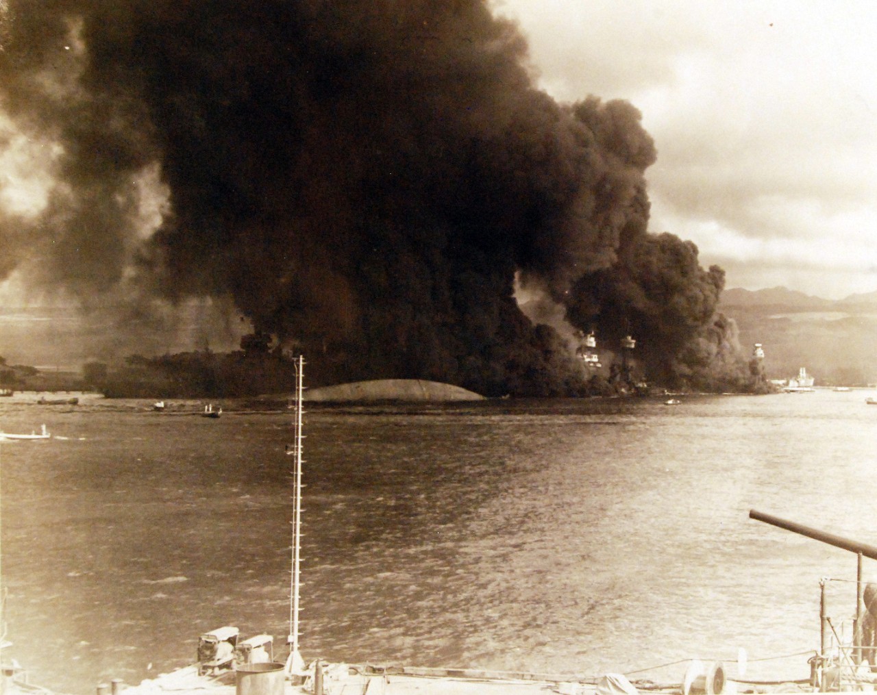 <p>80-G-32450: Japanese Attack on Pearl Harbor, December 7, 1941. View of “Battleship Row” during or immediately after the Japanese raid. The capsized USS Oklahoma (BB 37) is in the center, alongside USS Maryland (BB 46).</p>
