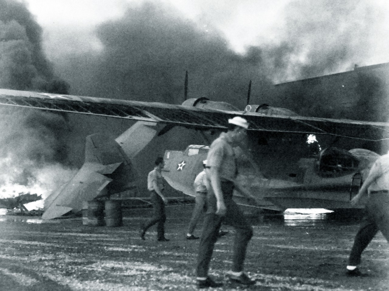 <p>80-G-32833: Japanese Attack on Pearl Harbor, December 7, 1941. KNOE 119 Rescue operations after the first attack and before bombing at Naval Air Station, Kaneohe Bay. Pulling a partially burning PBY aircraft from center of fire area.&nbsp;</p>
