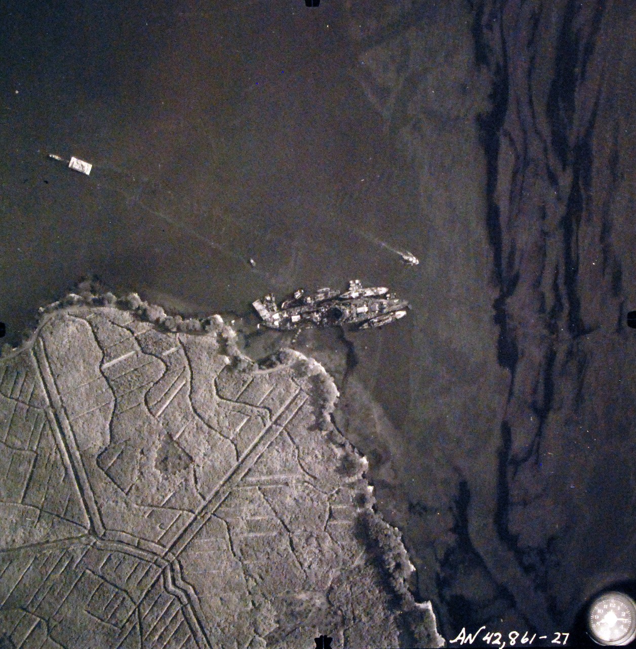 80-G-387588:  Pearl Harbor Attack, 7 December 1941.  Aerial view of "Battleship Row" moorings on the southern side of Ford Island, 10 December 1941, showing damage from the Japanese raid three days earlier.  USS Nevada (BB 36) is shown off Waipaio Point. Photographed by VJ-1 at an altitude of 3,000 feet and released November 9, 1950. U.S. Navy photograph, now in the collections of the National Archives.       (9/22/2015).