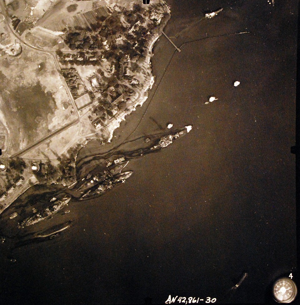 80-G-387587:  Pearl Harbor Attack, 7 December 1941.  Aerial view of "Battleship Row" moorings on the southern side of Ford Island, 10 December 1941, showing damage from the Japanese raid three days earlier.  USS Nevada (BB 36) is shown off Waipaio Point. Photographed by VJ-1 at an altitude of 3,000 feet and released November 9, 1950.  (9/22/2015).