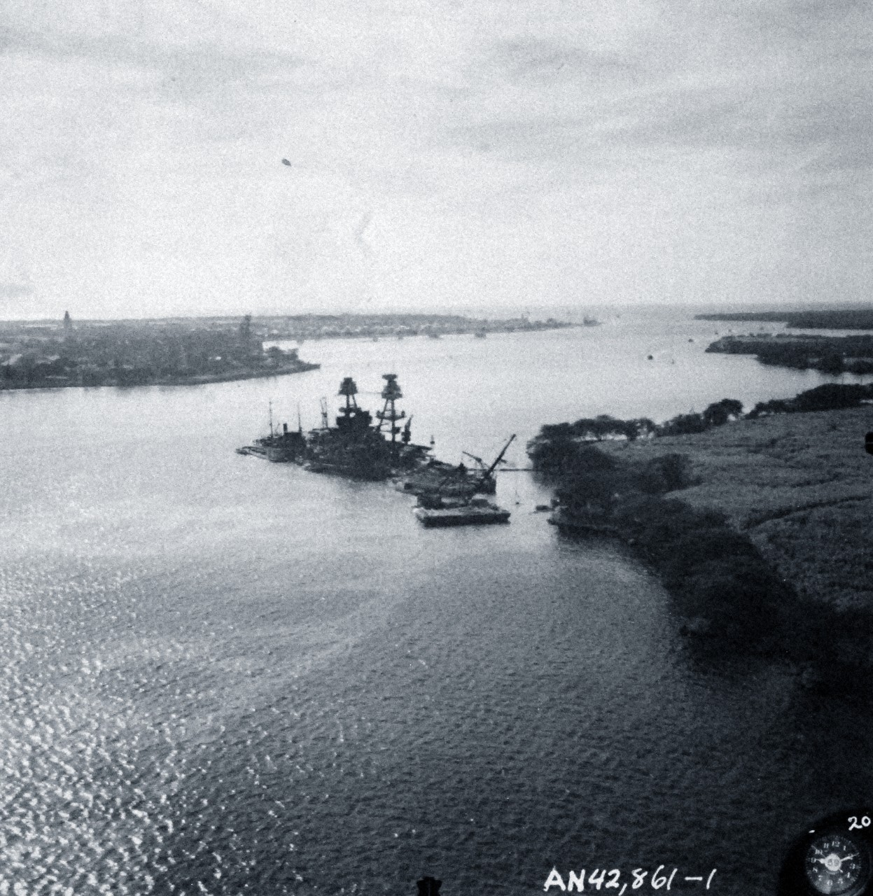 80-G-387563:  Japanese Attack at Pearl Harbor, December 7, 1941.   Aerial view of "Battleship Row" moorings on the southern side of Ford Island, 10 December 1941, showing damage from the Japanese raid three days earlier.  Battleship shown is USS Nevada (BB 36).  Photographed by VJ-1 at an altitude of 3,000 feet and released November 9, 1950. U.S. Navy photograph, now in the collections of the National Archives (9/22/2015).