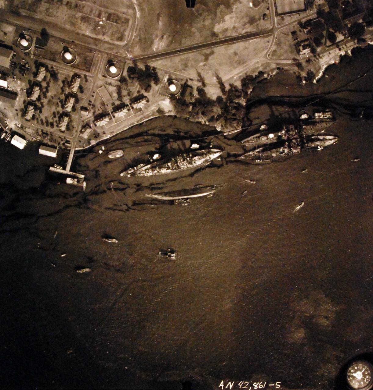 80-G-387566:  Pearl Harbor Attack, 7 December 1941.  Aerial view of "Battleship Row" moorings on the southern side of Ford Island, 10 December 1941, showing damage from the Japanese raid three days earlier.  Shown are: USS Oklahoma (BB-37), capsized; USS Tennessee (BB-43), lightly damaged, with the sunken USS West Virginia (BB-48).  Note dark oil streaks on the harbor surface, originating from the sunken battleships. Photographed by VJ-1 at an altitude of 3,000 feet and released November 9, 1950.  (9/22/2015).