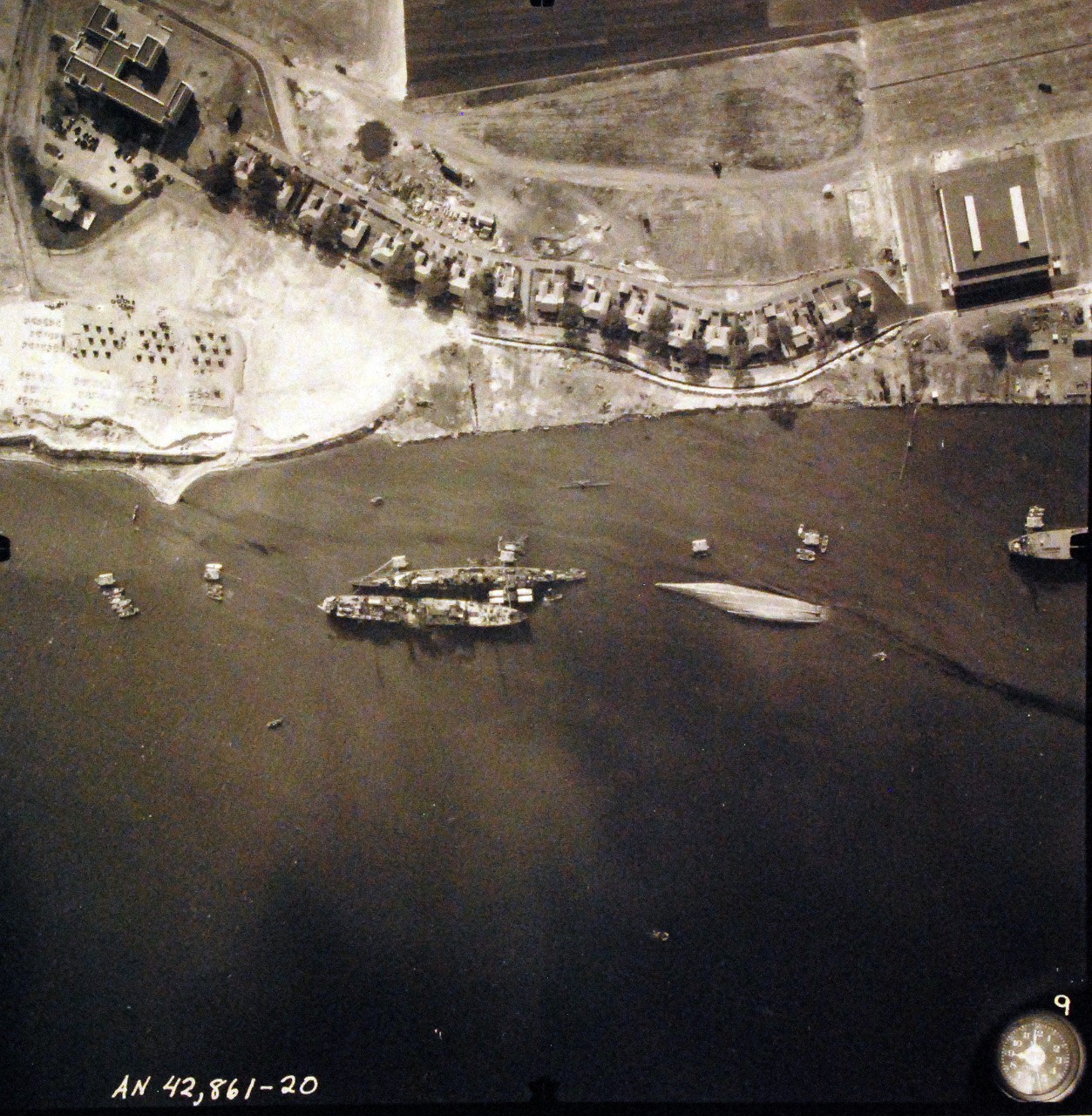 80-G-387581:  Pearl Harbor Attack, 7 December 1941.  Aerial view of "Battleship Row" moorings on the southern side of Ford Island, 10 December 1941, showing damage from the Japanese raid three days earlier.  Shown are USS Raleigh (CL 7), sunk, and USS Utah (BB 31), capsized.  Note dark oil streaks on the harbor surface, originating from the sunken battleships. Photographed by VJ-1 at an altitude of 3,000 feet and released November 9, 1950. U.S. Navy photograph, now in the collections of the National Archives.        (9/22/2015).