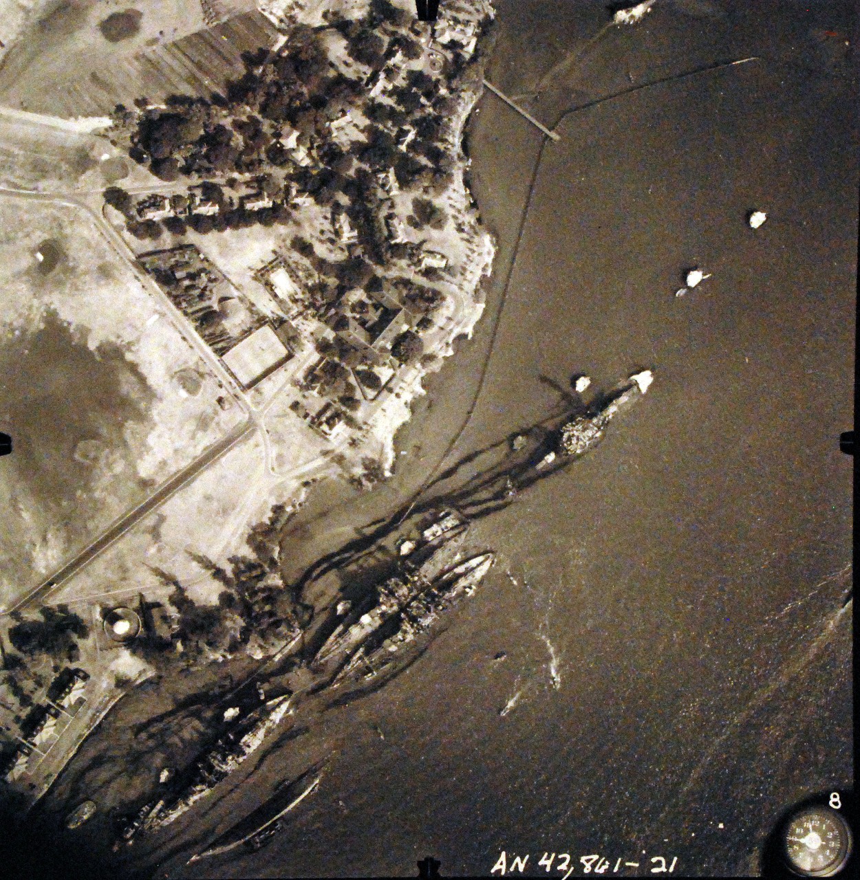 80-G-387582:  Pearl Harbor Attack, 7 December 1941.  Aerial view of "Battleship Row" moorings on the southern side of Ford Island, 10 December 1941, showing damage from the Japanese raid three days earlier.  Diagonally, from left center to lower right are: USS Maryland (BB-46), lightly damaged, with the capsized USS Oklahoma (BB-37) outboard. USS Tennessee (BB-43), lightly damaged, with the sunken USS West Virginia (BB-48) outboard. USS Arizona (BB-39), sunk, with her hull shattered by the explosion of the magazines below the two forward turrets. Note dark oil streaks on the harbor surface, originating from the sunken battleships. Photographed by VJ-1 at an altitude of 3,000 feet and released November 9, 1950.  U.S. Navy photograph, now in the collections of the National Archives.       (9/22/2015).