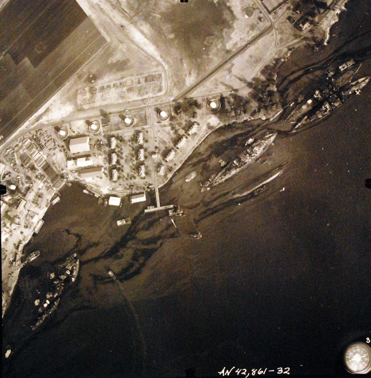 80-G-387592:  Pearl Harbor Attack, 7 December 1941.  Aerial view of "Battleship Row" moorings on the southern side of Ford Island, 10 December 1941, showing damage from the Japanese raid three days earlier.  Left, USS California (BB 44), then left to right, USS Maryland (BB-46), lightly damaged, with the capsized USS Oklahoma (BB-37) outboard. USS Tennessee (BB-43), lightly damaged, with the sunken USS West Virginia (BB-48) outboard. Note dark oil streaks on the harbor surface, originating from the sunken battleships. Photographed by VJ-1 at an altitude of 3,000 feet and released November 9, 1950.  U.S. Navy photograph, now in the collections of the National Archives.      (9/22/2015).