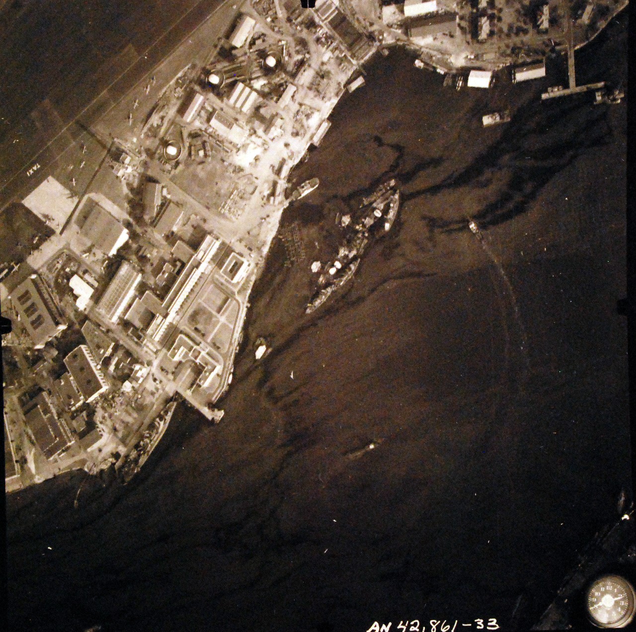 80-G-387593:  Pearl Harbor Attack, 7 December 1941.  Aerial view of "Battleship Row" moorings on the southern side of Ford Island, 10 December 1941, showing damage from the Japanese raid three days earlier.  USS California (BB 44) is shown.  Note dark oil streaks on the harbor surface, originating from the sunken battleships.  Photographed by VJ-1 at an altitude of 3,000 feet and released November 9, 1950. U.S. Navy photograph, now in the collections of the National Archives.       (9/22/2015).