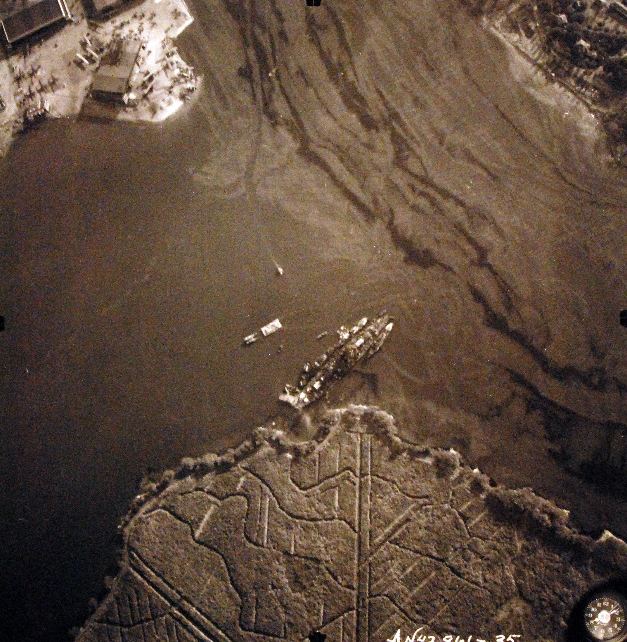 80-G-387595:  Pearl Harbor Attack, 7 December 1941.  Aerial view of "Battleship Row" moorings on the southern side of Ford Island, 10 December 1941, showing damage from the Japanese raid three days earlier.  USS Nevada (BB 36) is shown off Waipaio Point. Photographed by VJ-1 at an altitude of 3,000 feet and released November 9, 1950. U.S. Navy photograph, now in the collections of the National Archives.       (9/22/2015).