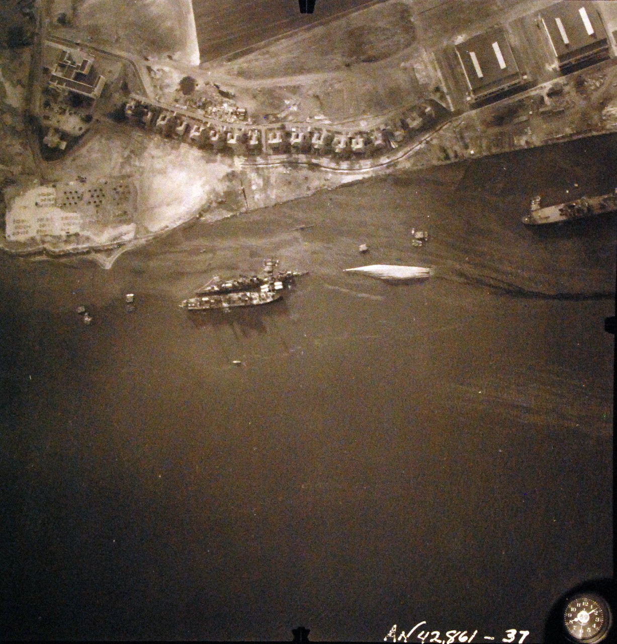 80-G-387596:  Pearl Harbor Attack, 7 December 1941.  Aerial view of "Battleship Row" moorings on the southern side of Ford Island, 10 December 1941, showing damage from the Japanese raid three days earlier.  Shown are USS Raleigh (CL 7), sunk, and USS Utah (BB 31), capsized.  Note dark oil streaks on the harbor surface, originating from the sunken battleships. Photographed by VJ-1 at an altitude of 3,000 feet and released November 9, 1950. U.S. Navy photograph, now in the collections of the National Archives.       (9/22/2015).