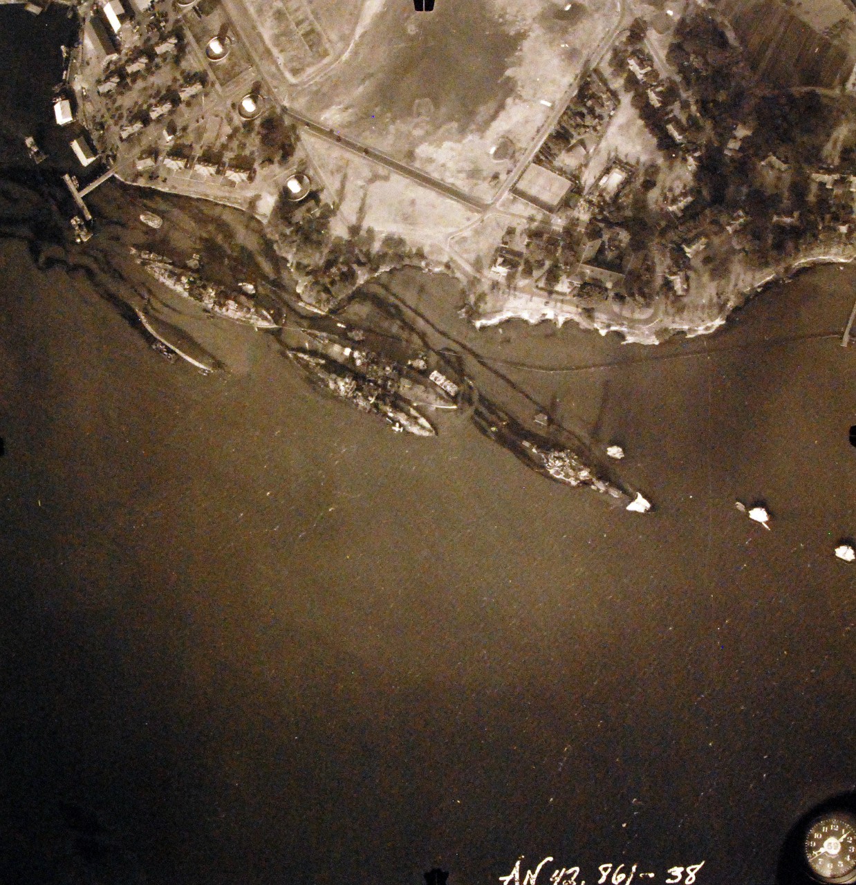 80-G-387597:  Pearl Harbor Attack, 7 December 1941.  Aerial view of "Battleship Row" moorings on the southern side of Ford Island, 10 December 1941, showing damage from the Japanese raid three days earlier.  Diagonally, from left center to lower right are: USS Maryland (BB-46), lightly damaged, with the capsized USS Oklahoma (BB-37) outboard. USS Tennessee (BB-43), lightly damaged, with the sunken USS West Virginia (BB-48) outboard. USS Arizona (BB-39), sunk, with her hull shattered by the explosion of the magazines below the two forward turrets. Note dark oil streaks on the harbor surface, originating from the sunken battleships. Photographed by VJ-1 at an altitude of 3,000 feet and released November 9, 1950.  U.S. Navy photograph, now in the collections of the National Archives.      (9/22/2015).