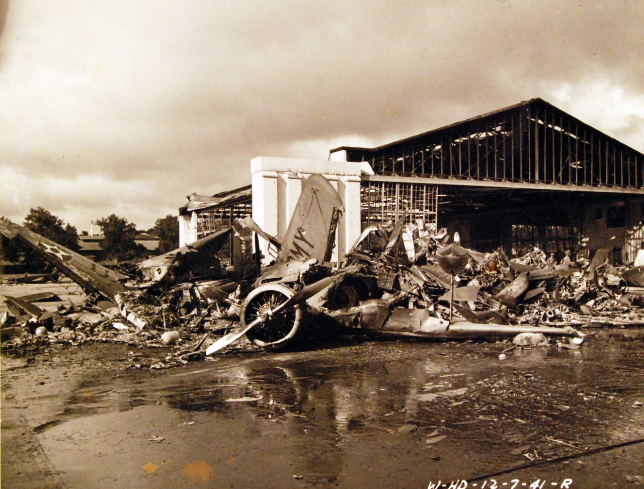 <p>80-G-32896: Japanese Attack on Pearl Harbor, December 7, 1941. Wheeler Field. U.S. aircraft destroyed as a result of the Japanese bombing. The heap of demolished planes wrecked with hangar in the background. An Army Amphibian is in the foreground.&nbsp;</p>

