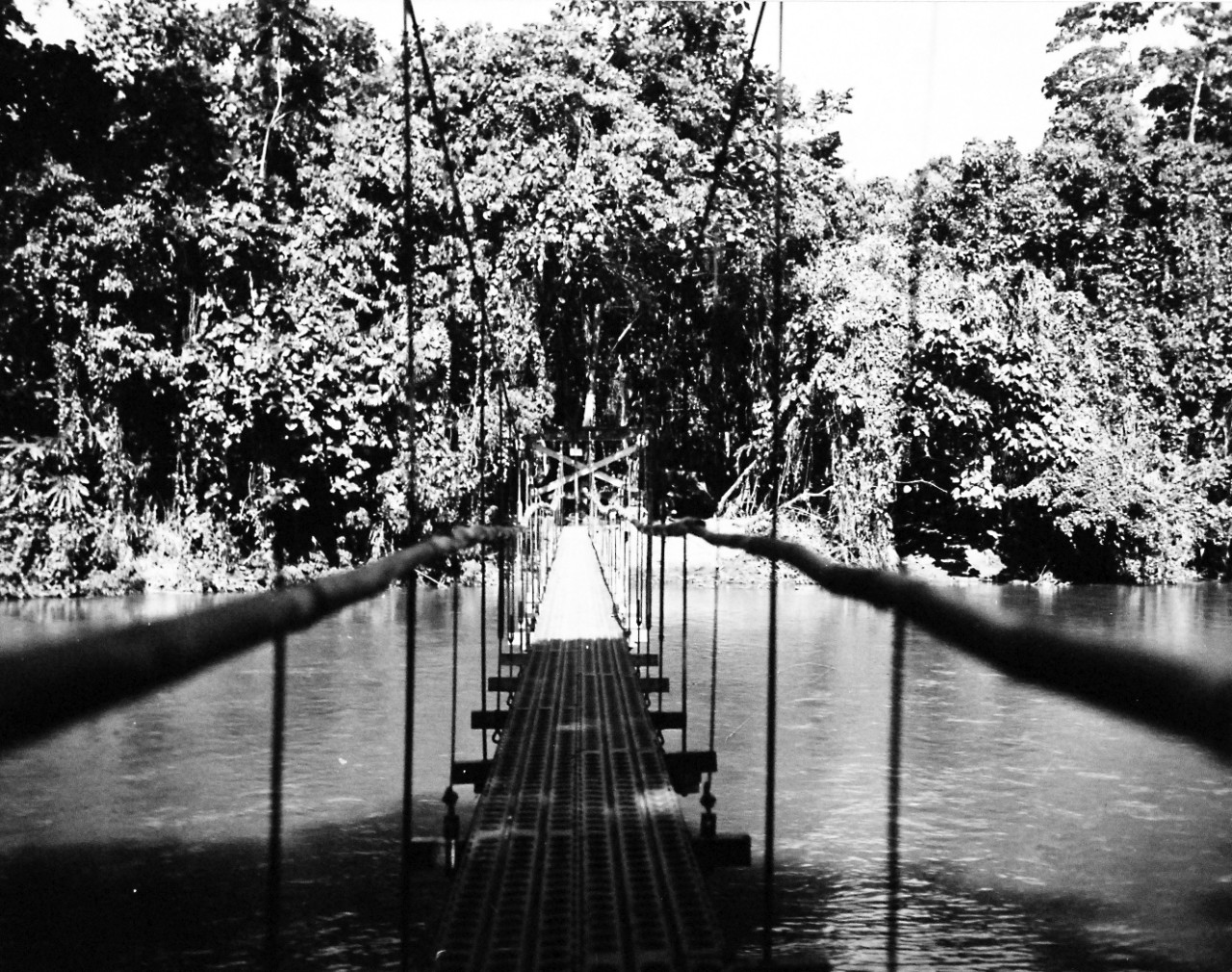 <p>80-G-44225:&nbsp; Guadalcanal Campaign, August 1942-February 1943.&nbsp; Seabees cross their bridges.&nbsp; This bridge over a river on Guadalcanal was erected in a day and a half.&nbsp; Flooring is pierced plank, handrails are of native bamboo, and he towers were bents from a portable military engineer bridge.&nbsp; Photograph received March 2, 1944.&nbsp; &nbsp;</p>
