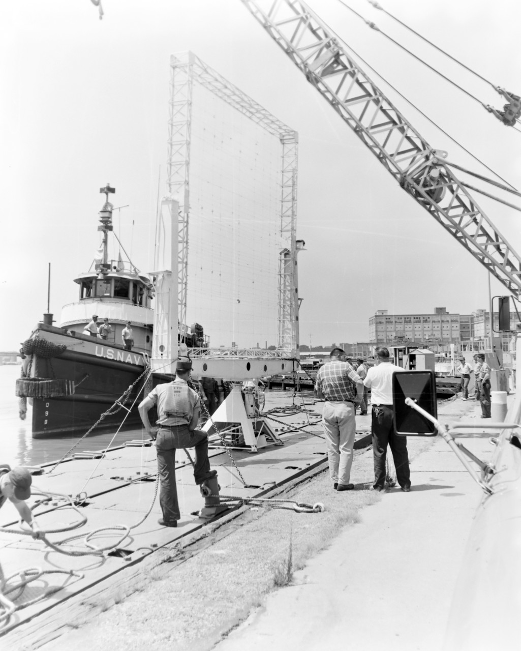 NMUSN-1012:   XAF Radar Antenna, 1960s.   Being delivered to the Washington Navy Yard for display.  Note the U.S. Navy tug alongside a small thin barge carrying the radar antenna.  The tug appears to be USS Wahtah (YTB-140).  This radar was the first shipboard radar to be installed onboard a U.S. Navy ship, USS New York (BB-34).  Surviving World War II, it was brought to the Washington Navy Yard where it was on exterior display until the mid-1980s where it was placed into storage.   Following conservation, the radar is now on display at the National Electronics Museum, Linthicum, Maryland.    Original is a black and white negative.   National Museum of the U.S. Navy Photograph Collection.