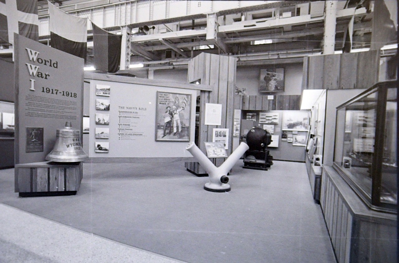 NMUSN-1255 World War I exhibit area, 1973. View shows the entrance, Y-Gun, and Mk6 Mine, along with the USS Wyoming bell. Original is a film strip. National Museum of the U.S. Navy Photograph Collection.