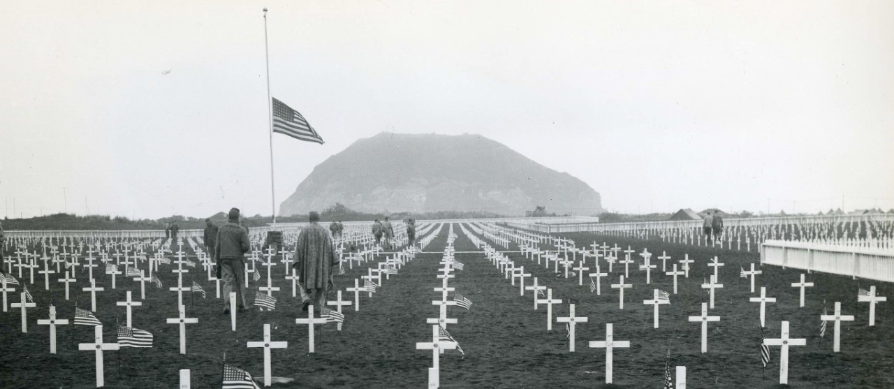 <p>A graveyard in honor of those who gave the ultimate sacrifice, Iwo Jima. In the background the United States Flag flies at half-mast in front of Mt. Suribachi.&nbsp;</p>
