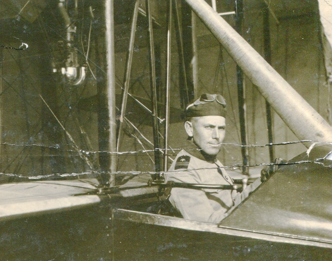Portrait of a man in uniform in the pilot seat of a biplane. 